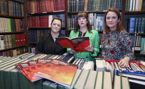 Three researchers pictured holding a report in a library