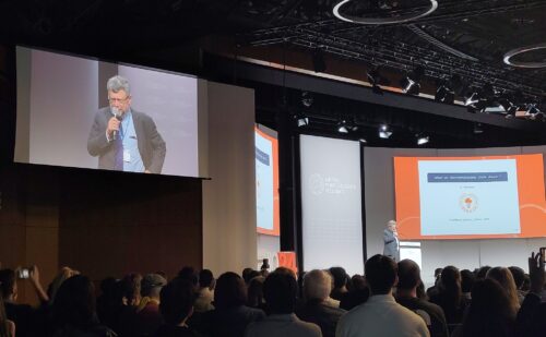 Image of lecture hall with man speaking holding microphone